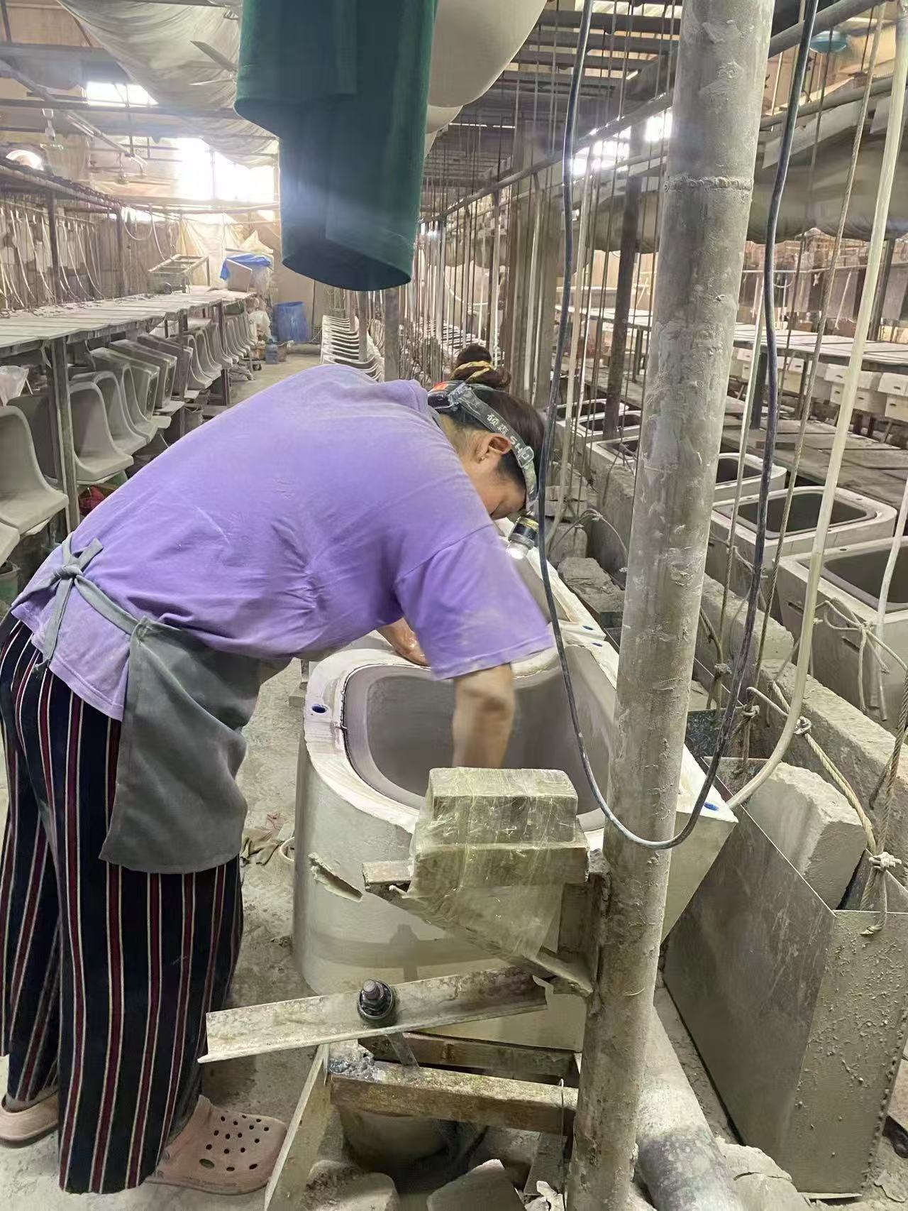 Person in a factory setting working on a toilet seat assembly line.